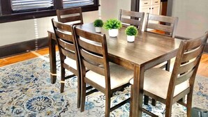 A dining area with a wooden table and chairs, a patterned rug, and a chandelier. - Modern Midtown Retreat (Montgomery)