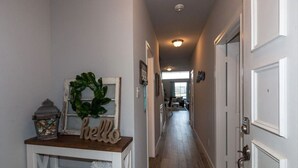 A hallway with a wooden bench, a 'hello' sign, a wreath, and a lantern.