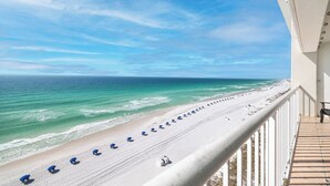 Een balkon met uitzicht op een strand met parasols.