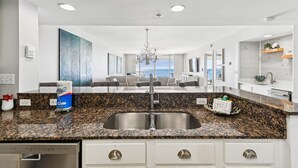 Una cocina moderna con encimeras de granito, pileta de acero inoxidable y muebles color blanco.