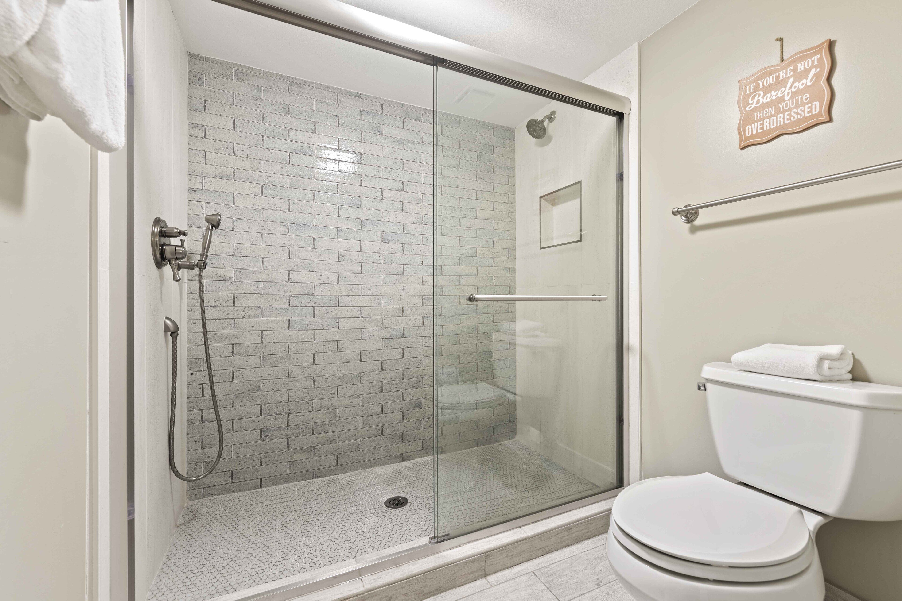 A bathroom with a glass-enclosed shower, a white toilet, and a towel rack.