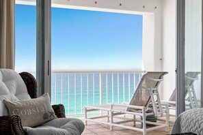 A balcony with a view of the ocean, white furniture, and a wicker chair. - Gone Coastal - Destin Gulfgate 1103! (Destin)