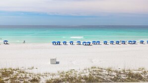 Una playa de arena blanca, una fila de sombrillas azules y un océano azul cristalino.