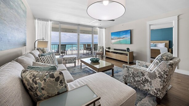 A spacious living area with a large sofa, a coffee table, and a TV. There is a balcony with a view of the ocean. - Wait 'n Sea - Destin Gulfgate 0205! (Destin)