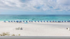 A beach with white sand, a row of blue umbrellas, and the ocean in the background. - Wait 'n Sea - Destin Gulfgate 0205! (Destin)