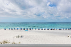 Una playa de arena blanca, una fila de sombrillas azules y el océano al fondo.
