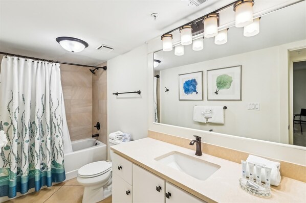 A modern bathroom with a bathtub, toilet, sink, and a large mirror with lights. - Hook, Wine & Sinker - Destin Gulfgate 0304! (Destin)
