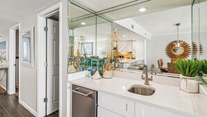 Uma cozinha moderna com uma ilha grande, eletrodomésticos de aço inoxidável e uma parede de proteção de vidro.