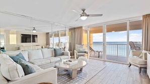 A spacious living room with a large sofa, a coffee table, and a ceiling fan. There is a balcony with a view of the ocean. - Feeling tip'Sea - Destin Gulfgate 0403! (Destin)