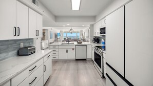 Una cucina moderna con mobili bianchi, un'isola centrale e vista all'esterno.