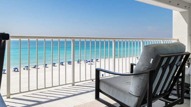 Un balcone con vista sulla spiaggia, una sedia e un tavolo.