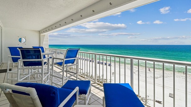 Ein Balkon mit blauen Stühlen und Blick auf den Strand.
