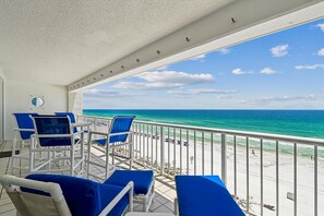 Un balcon avec des chaises bleues et une vue sur la plage.