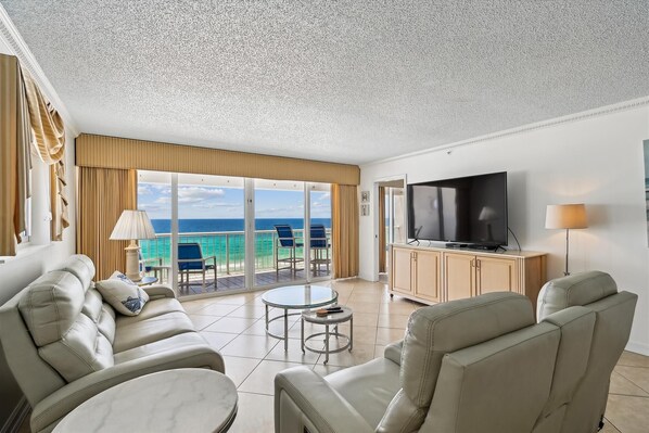 Une chambre d’hôtel avec un balcon, une télévision, un canapé et une table.