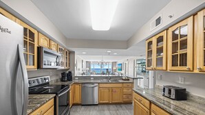 A modern kitchen with wooden cabinets, stainless steel appliances, and a large island. - Reel Paradise - Destin Gulfgate 0505! (Destin)