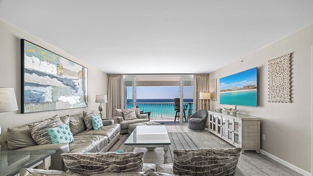 A spacious living room with a large window overlooking the ocean, a sofa set, a coffee table, and a television. - Reel Paradise - Destin Gulfgate 0505! (Destin)