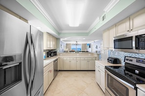 A modern kitchen with stainless steel appliances, a large island, and a view to the outside.