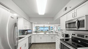 A modern kitchen with stainless steel appliances, white cabinetry, and a view to the outside. - Good Times and Tan Lines - Destin Gulfgate 0603! (Destin)