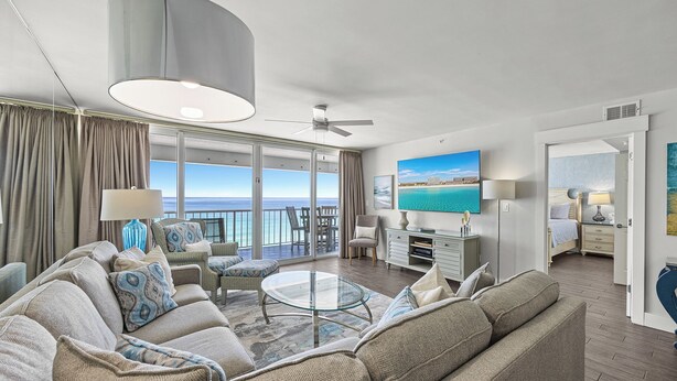 A spacious living room with a large sofa, a glass coffee table, and a view of the ocean through large windows. - Good Times and Tan Lines - Destin Gulfgate 0603! (Destin)