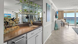 Una cocina moderna con un gran salpicadero de vidrio, un comedor con vista al océano y un balcón con vistas.