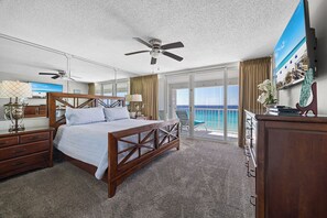Une chambre d’hôtel avec un lit, un ventilateur de plafond, une télévision et un balcon donnant sur l’océan.