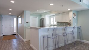 Una cocina moderna con una isla central, taburetes de bar y un refrigerador.