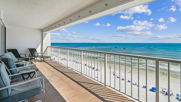 Ein Balkon mit Blick auf den Strand, ausgestattet mit Stühlen und einem Geländer.