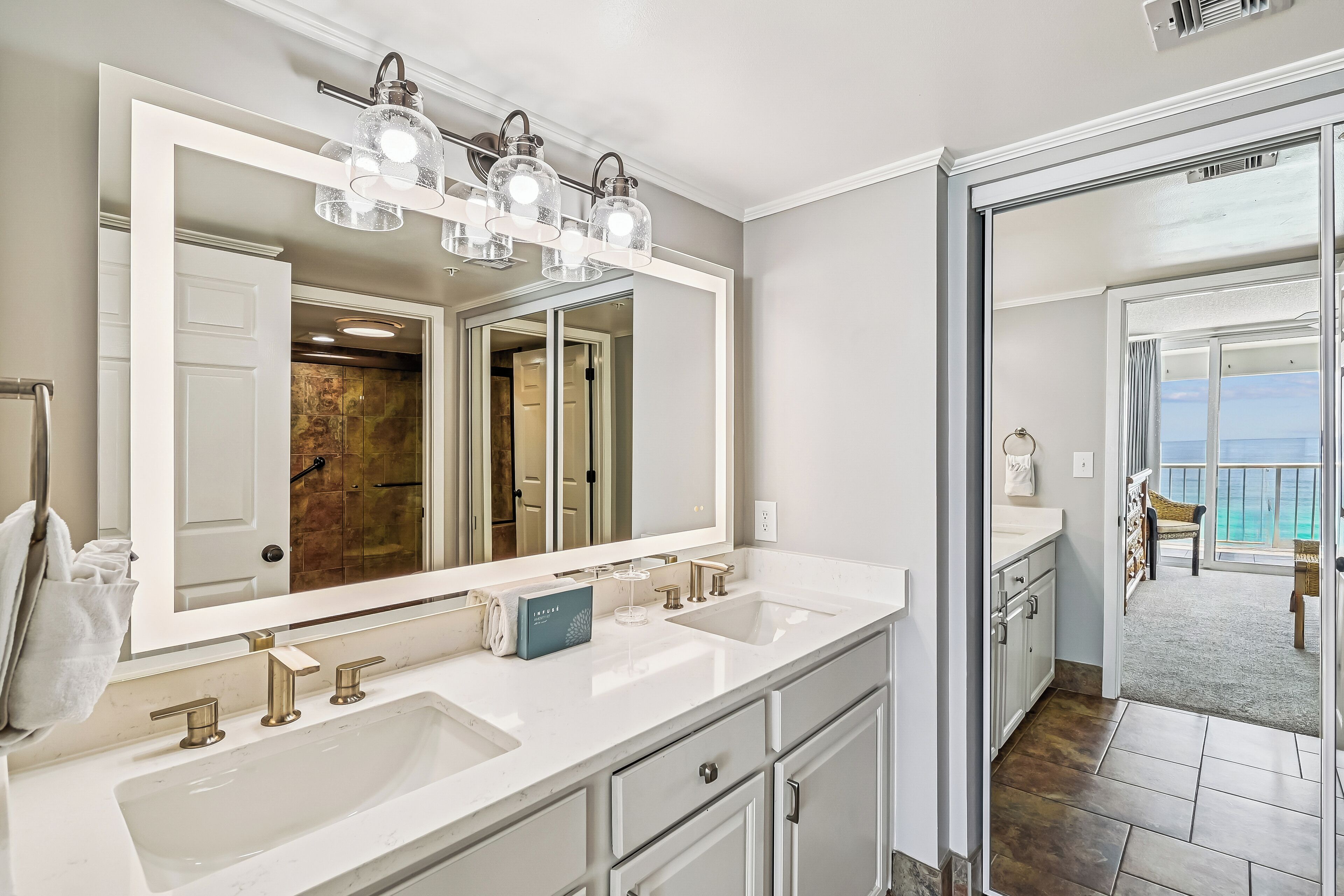 A bathroom with a large mirror, two sinks, and a vanity.
