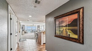 Ein Flur mit Blick auf einen Balkon und einen Essbereich, der zu einer Küche mit einem großen Fenster führt.