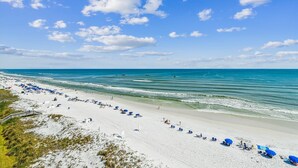 Ein Strand mit weißem Sand, klarem, blauem Wasser und einigen Sonnenschirmen.