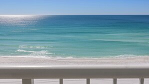 A beach view with clear blue water and a white sandy shore.