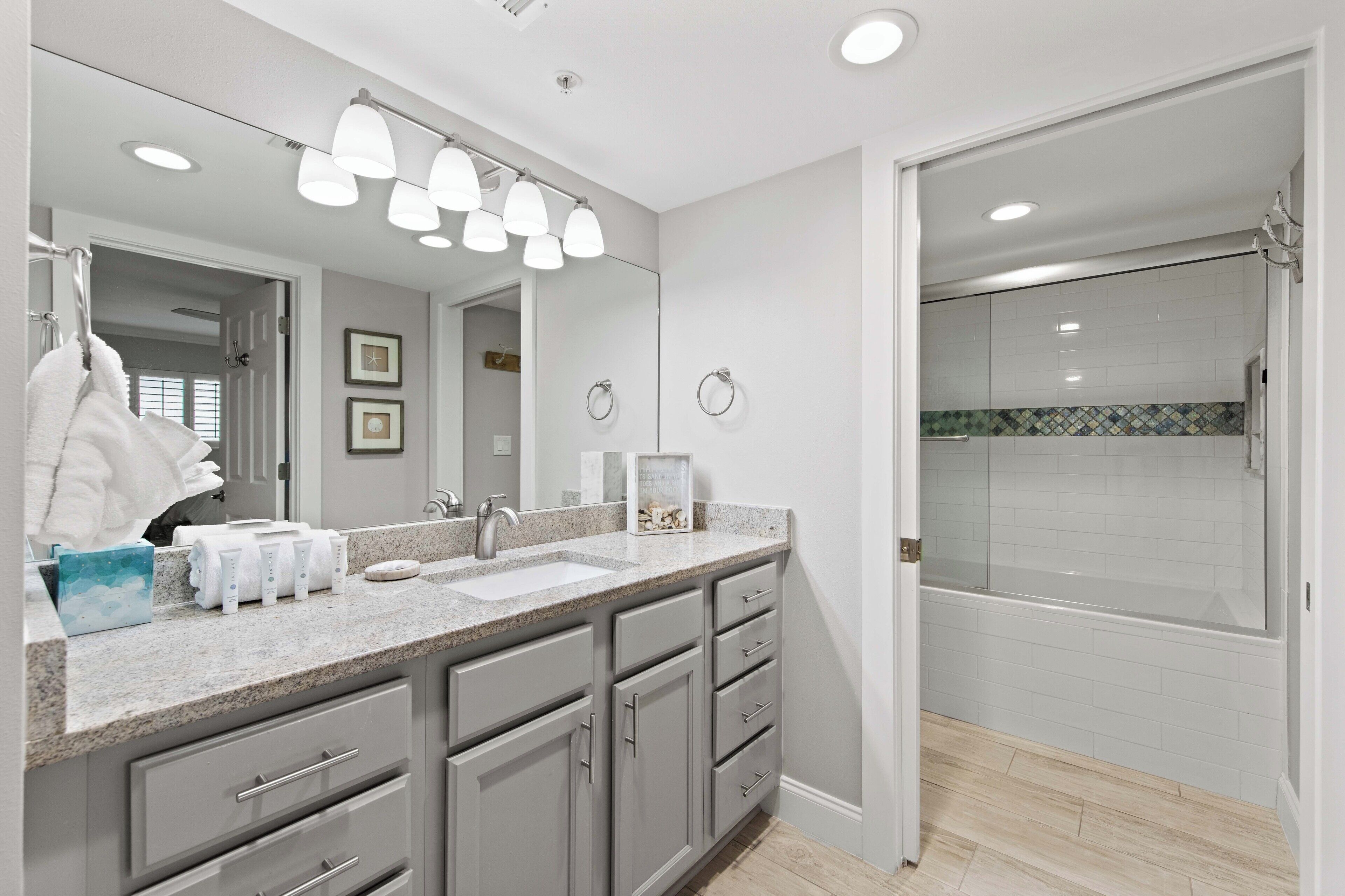 Une salle de bain moderne avec un grand miroir, un lavabo et un espace douche.