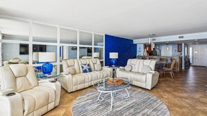 A spacious living room with a large sofa set, a glass coffee table, and a dining area with chairs and a table. - Off the Hook - Destin Gulfgate 0802! (Destin)