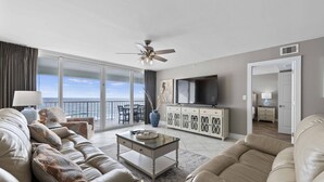 A modern living room with a sofa, coffee table, and TV, a balcony with a view, and a ceiling fan. - Beachy Keen - Destin Gulfgate 0805! (Destin)