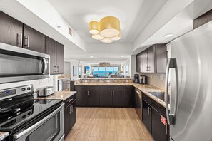 A modern kitchen with dark cabinetry, stainless steel appliances, and a central island. - Starfish Shack - Destin Gulfgate 0806! (Destin)