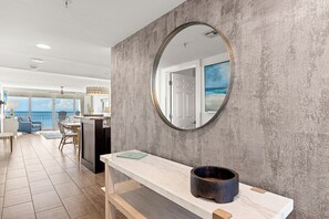 A modern interior with a round mirror, a marble countertop, and a view of the ocean through a door. - Starfish Shack - Destin Gulfgate 0806! (Destin)