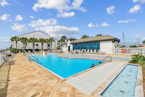 Ein Schwimmbecken mit Rutsche, Liegestühlen und einem Gebäude mit der Aufschrift 'Gulfstream Fitness Center'.