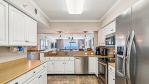 Une cuisine moderne avec des meubles blancs, des appareils en acier inoxydable et une vue sur l’extérieur.