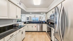 A modern kitchen with white cabinets, stainless steel appliances, and a black countertop. - All Decked Out - Destin Gulfgate 0904! (Destin)
