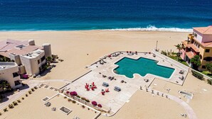 Vue aérienne d’un complexe hôtelier doté d’une piscine centrale, d’un accès à la plage et offrant une vue sur l’océan.