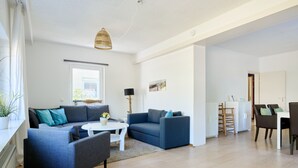 Ein modernes Wohnzimmer mit einer Sofagarnitur, einem Essbereich und einer Küche im Hintergrund.