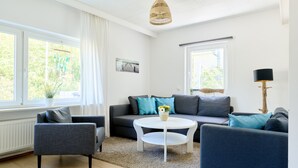 Ein modernes Wohnzimmer mit einem grauen Sofa, einem weißen Couchtisch und einer Stehlampe.