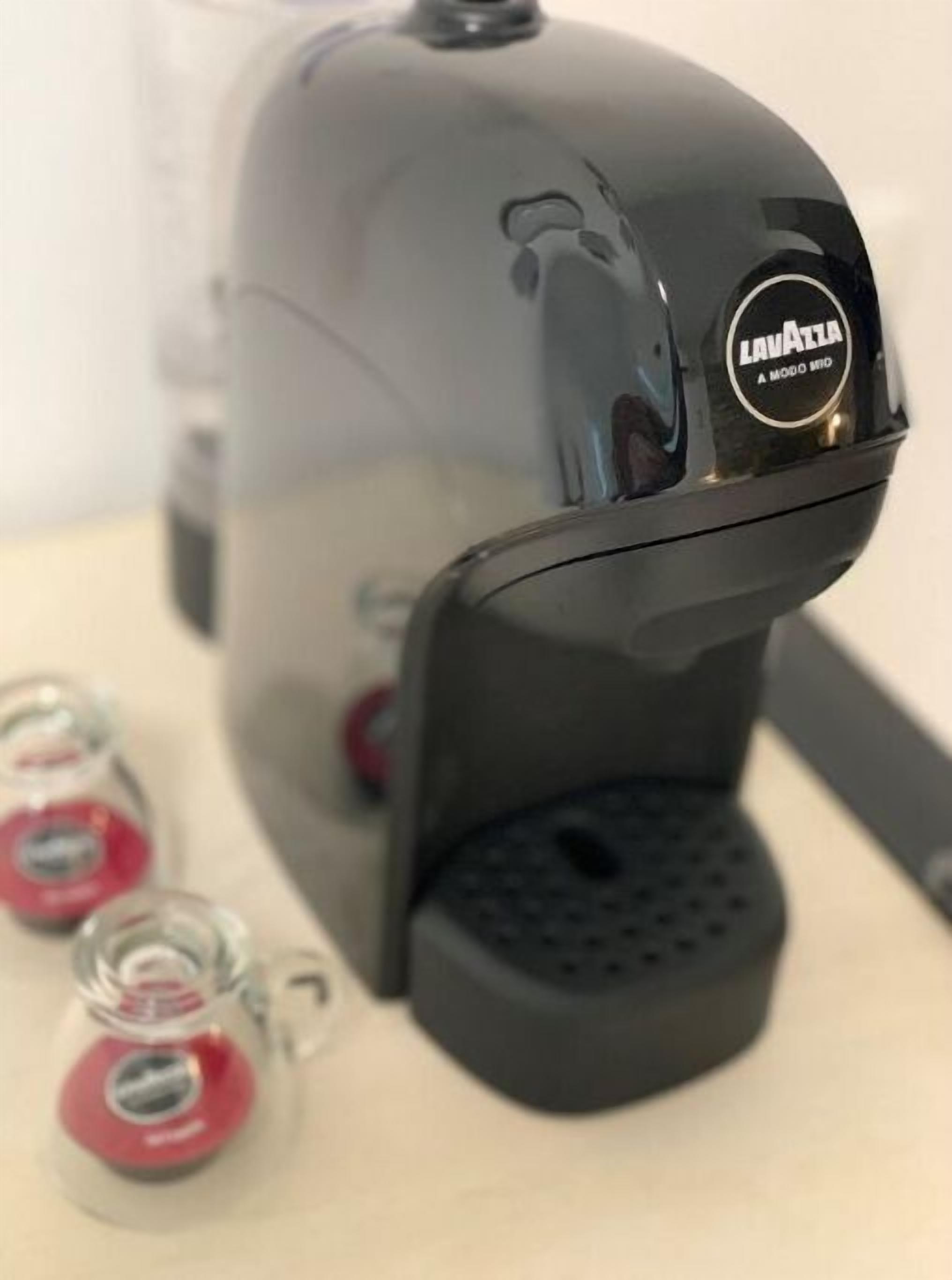 A black portable espresso machine with a clear water tank and a drip tray.