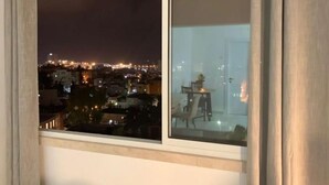 Vista nocturna desde una ventana con vistas a un paisaje urbano de edificios y luces.