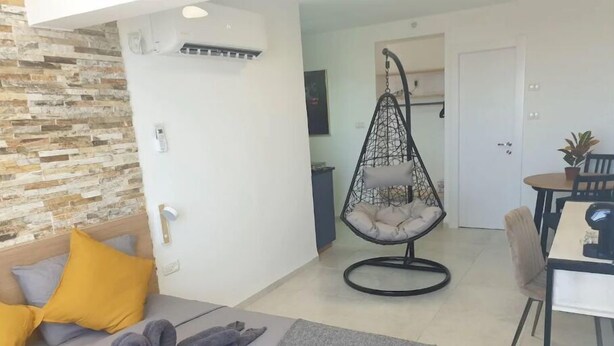 Una habitación de hotel moderna con una cama, un sillón colgante y una zona de comedor.