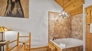 Ein Badezimmer mit einer Holzwanne, einem Holzstuhl, einer Bank, einem Waschbecken und einer Kristallleuchtreiter.