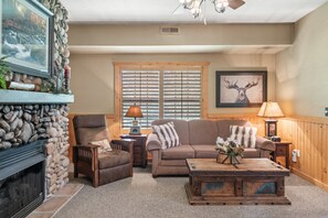 A cozy living room with a stone fireplace, a comfortable couch, and a wooden coffee table.