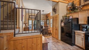 A kitchen with a black refrigerator, wooden cabinets, and a staircase leading to an upper level. - Spacious, Luxury 2BR+Loft Cabin with Fireplace & Balcony - Close to Entertainment! (Branson)