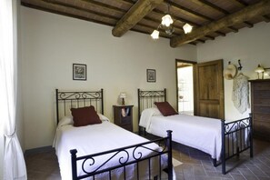 A bedroom with two beds, wooden beams on the ceiling, and a wooden door. - Apartment "Arco": (Pietraviva)