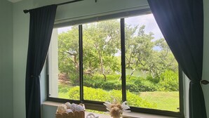 Ett rum med ett stort fönster, en korg av rotting och en vas med blommor på fönsterbrädan.